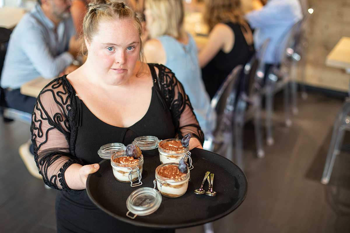 Femme porteuse de trisomie 21 travaillant dans un restaurant inclusif