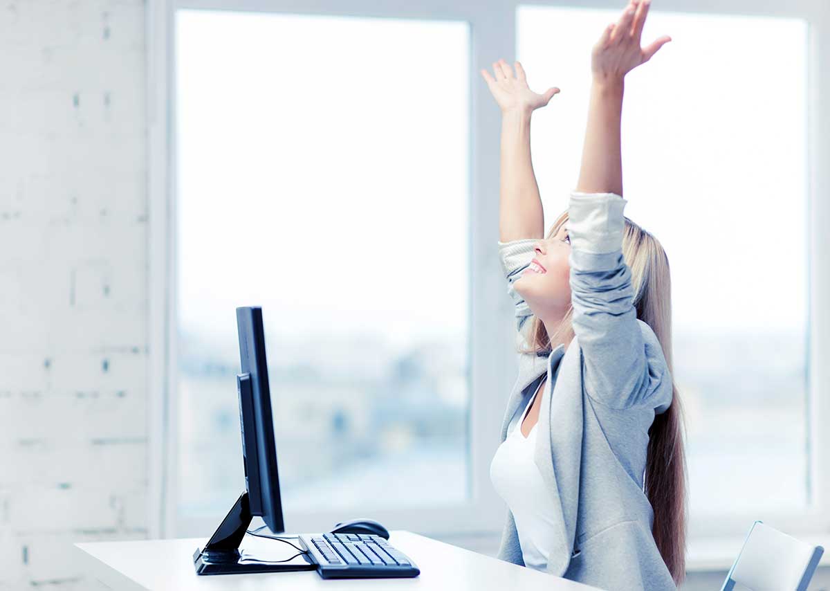 Collaboratrice levant les bras de satisfaction devant son écran