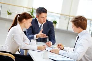 Trois collaborateurs en réunion de travail autour de documents chiffrés