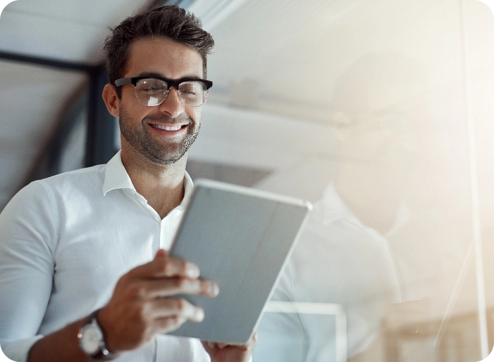 Homme souriant consultant une tablette dans un bureau lumineux