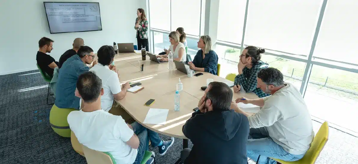 Réunion d'équipe autour d'une table, présentation projetée à l'écran