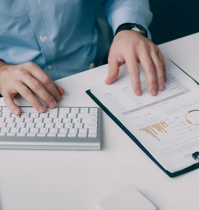 Mains sur un clavier à côté d'un rapport imprimé avec graphiques