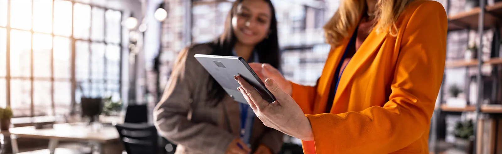 Deux collaboratrices consultant une tablette dans un bureau industriel