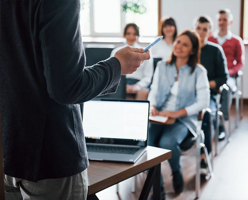 Formateur s'adressant à un groupe de participants assis en salle de formation