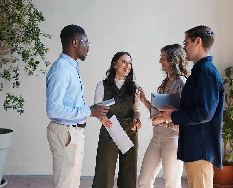 Quatre collègues en discussion debout, tablettes et documents en main