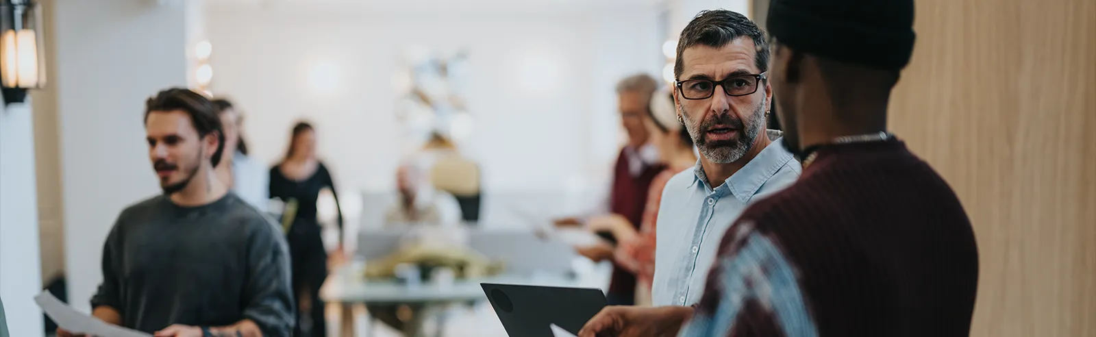 Collaborateurs en mouvement dans un couloir d'entreprise, documents en main