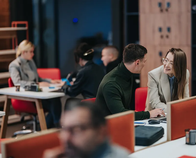 Deux collègues en discussion devant un ordinateur portable dans un espace de travail