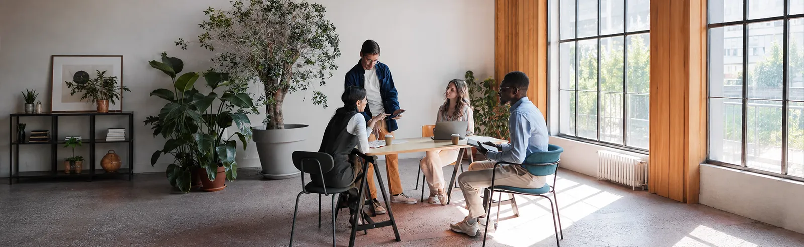 Quatre personnes en réunion informelle autour d'une table haute