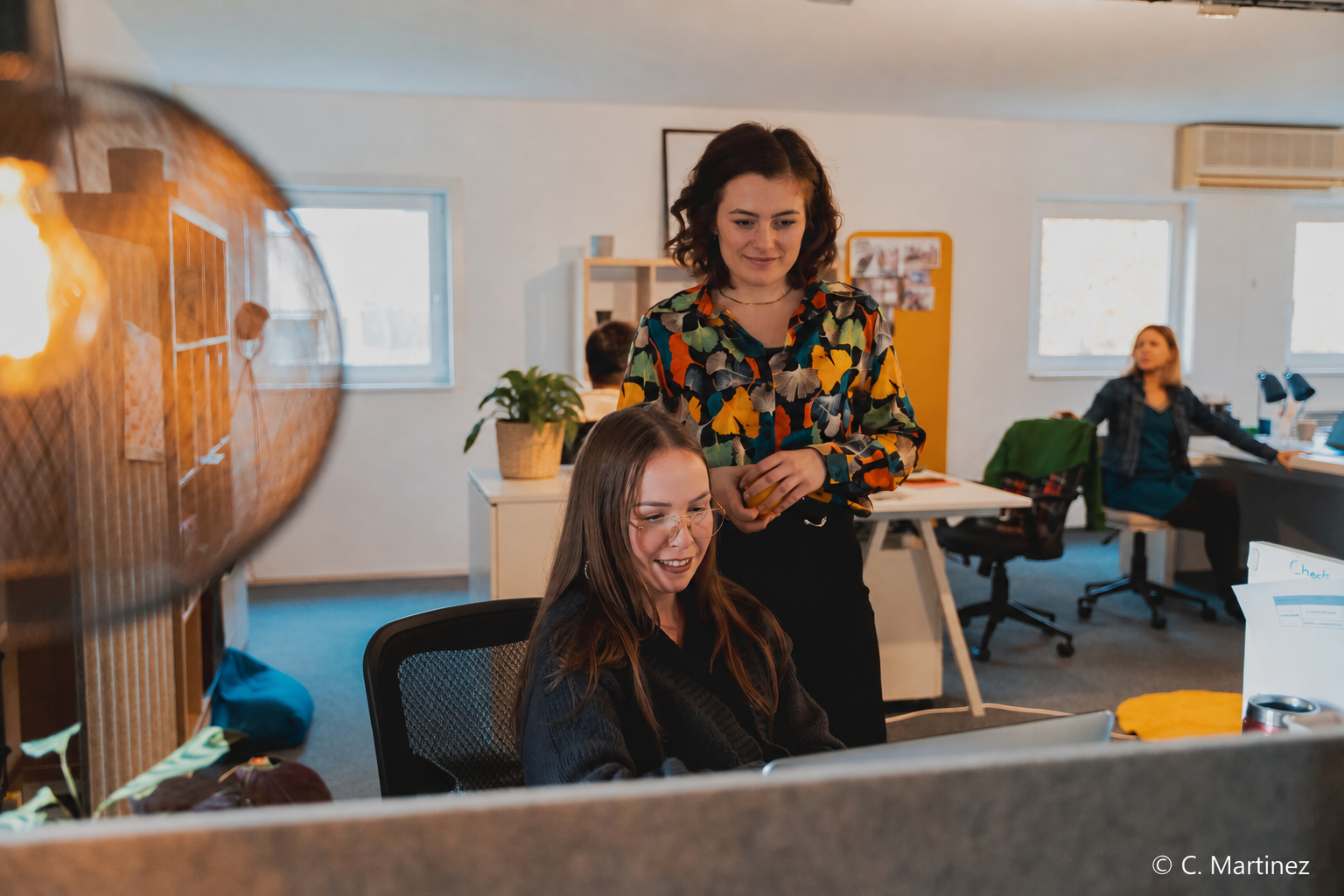 Deux collaboratrices One RH souriantes devant un écran dans un open space