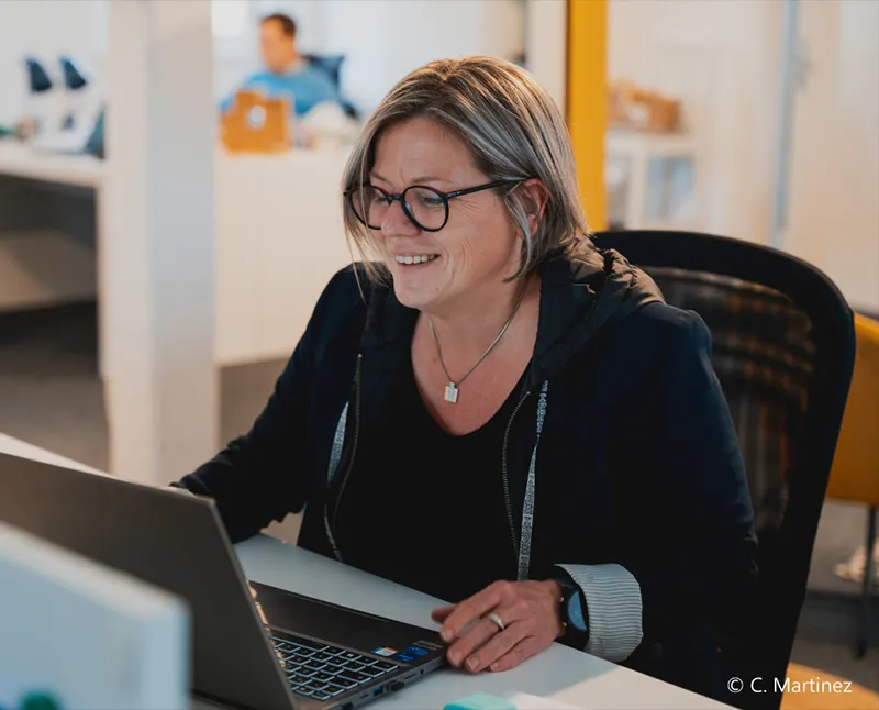 Consultante One RH souriante devant son ordinateur portable