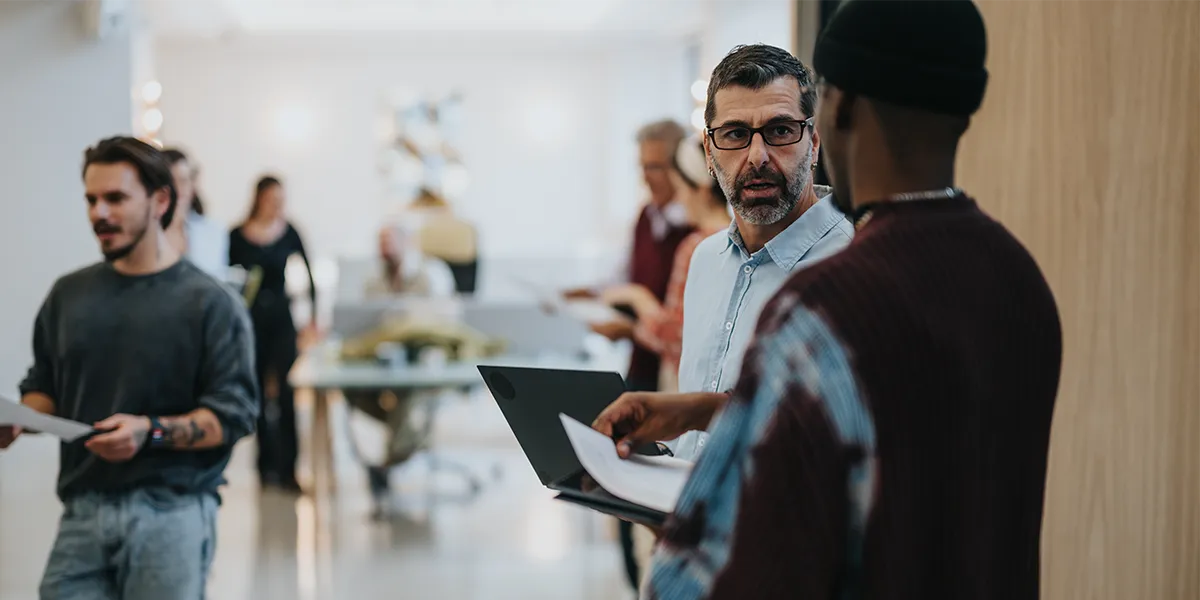Collaborateurs en mouvement dans un couloir d'entreprise, documents en main