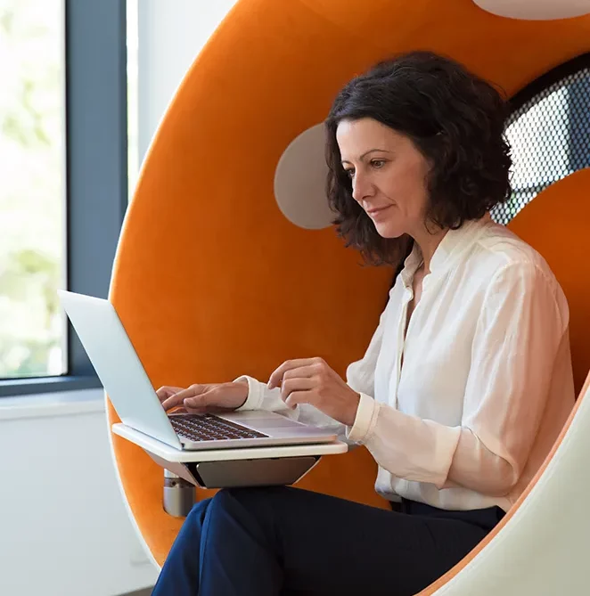 Femme travaillant sur un ordinateur portable dans un fauteuil-cocon