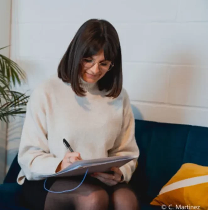 Consultante One RH prenant des notes sur un carnet, assise sur un canapé