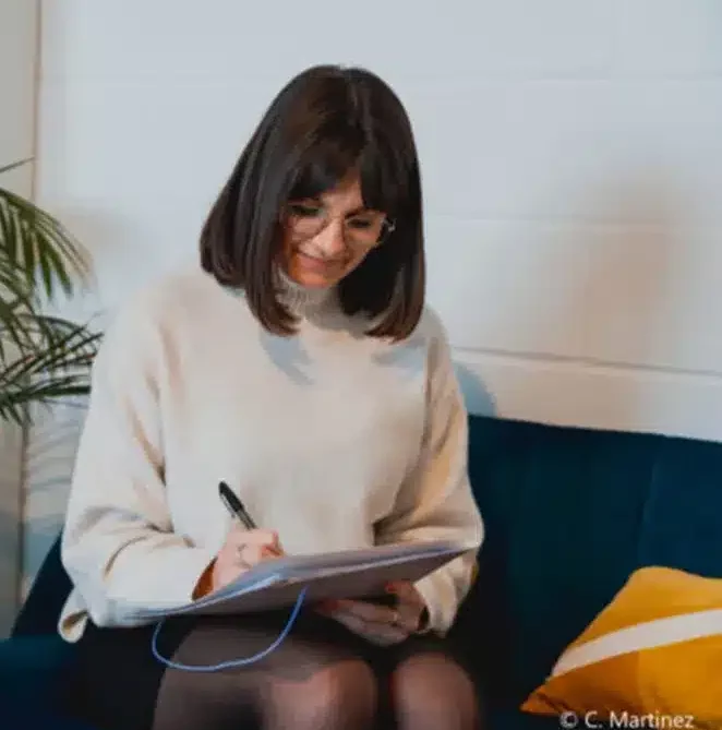 Consultante One RH prenant des notes sur un carnet, assise sur un canapé